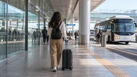 A traveler rolling luggage between airport and ground transport.