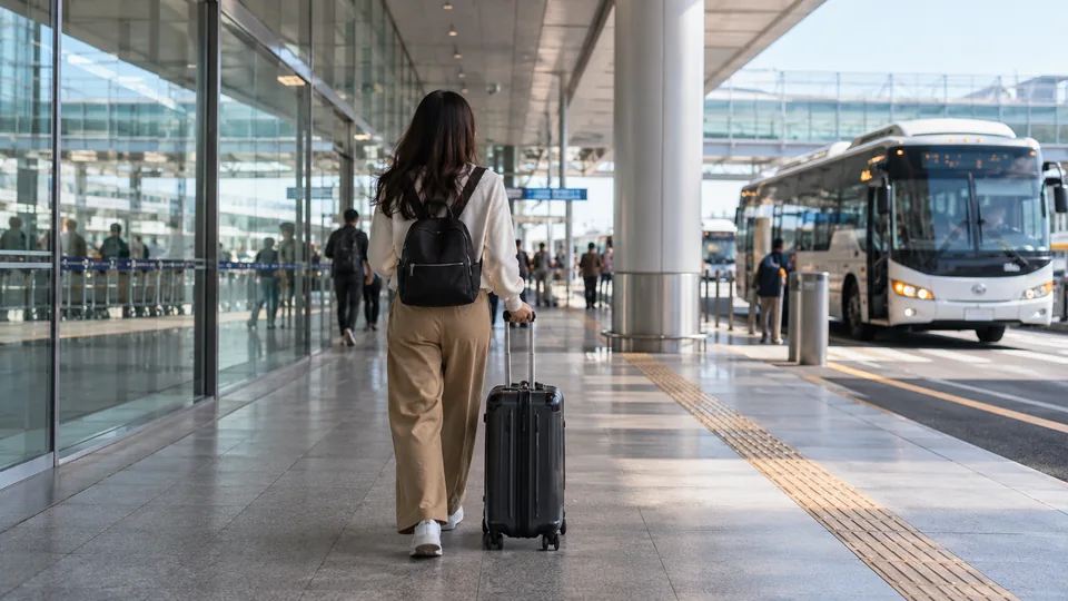 A traveler rolling luggage between airport and ground transport.