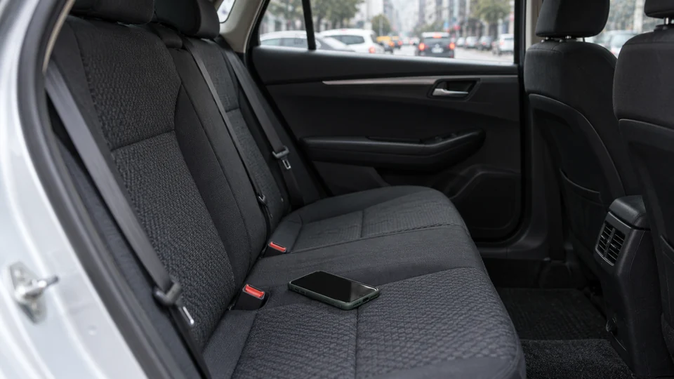 A smartphone in a green case left on the rear seat of a sedan