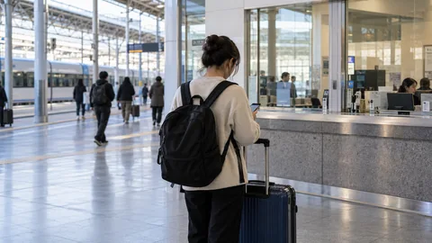 A traveler checking a phone on a station concourse.