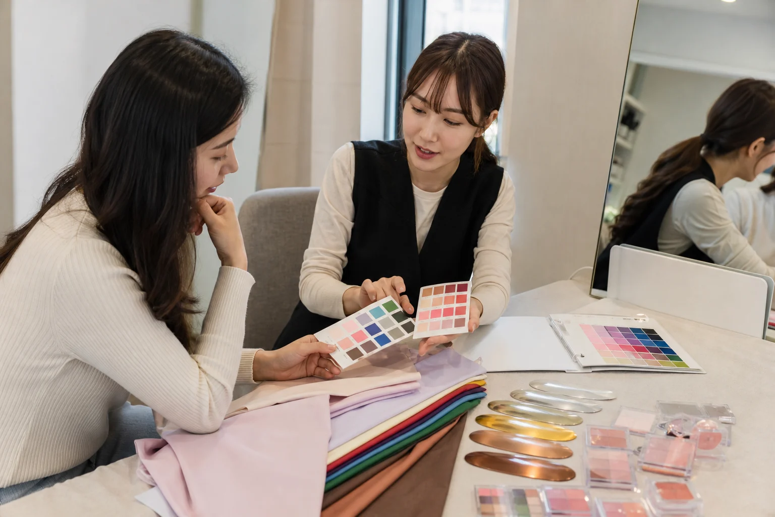 Client and consultant reviewing color cards, fabric, metal samples, and makeup shades